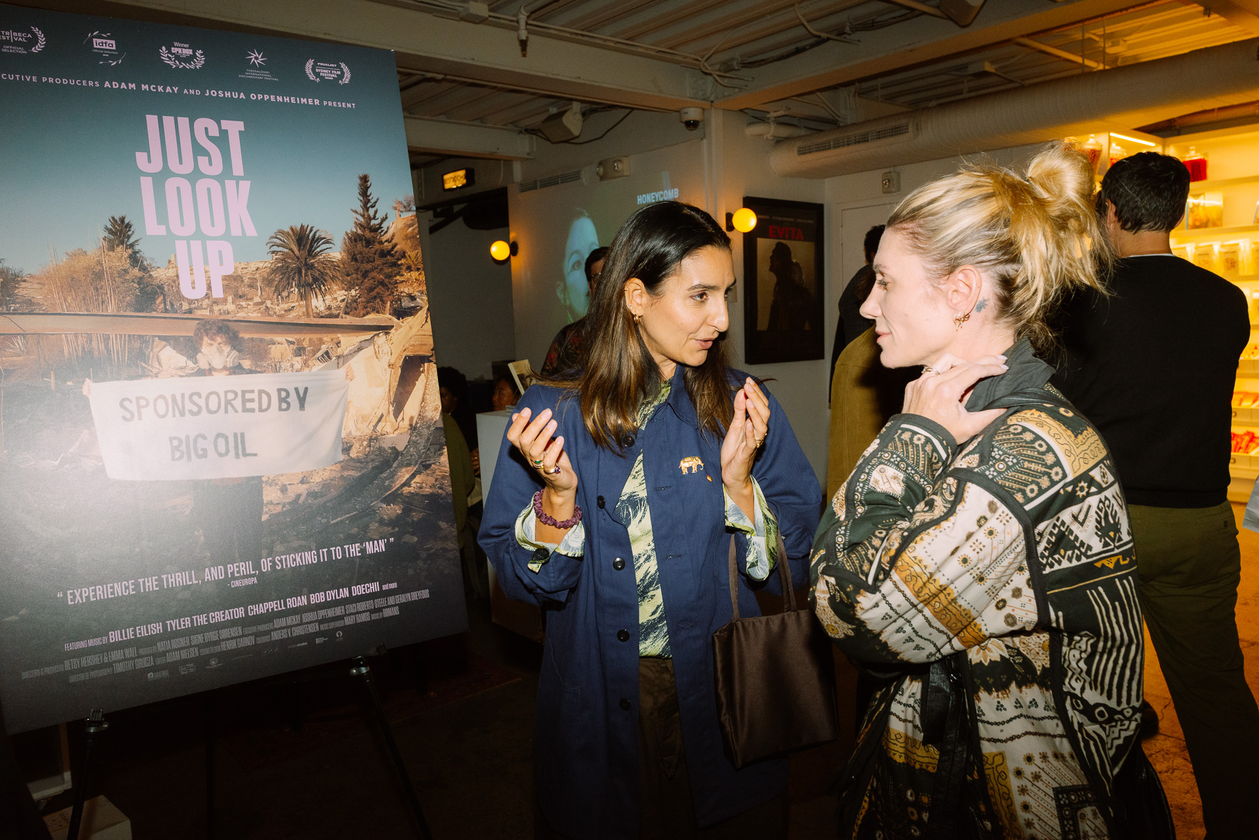 Guests talking beside the Just Look Up poster in the Metrograph lobby