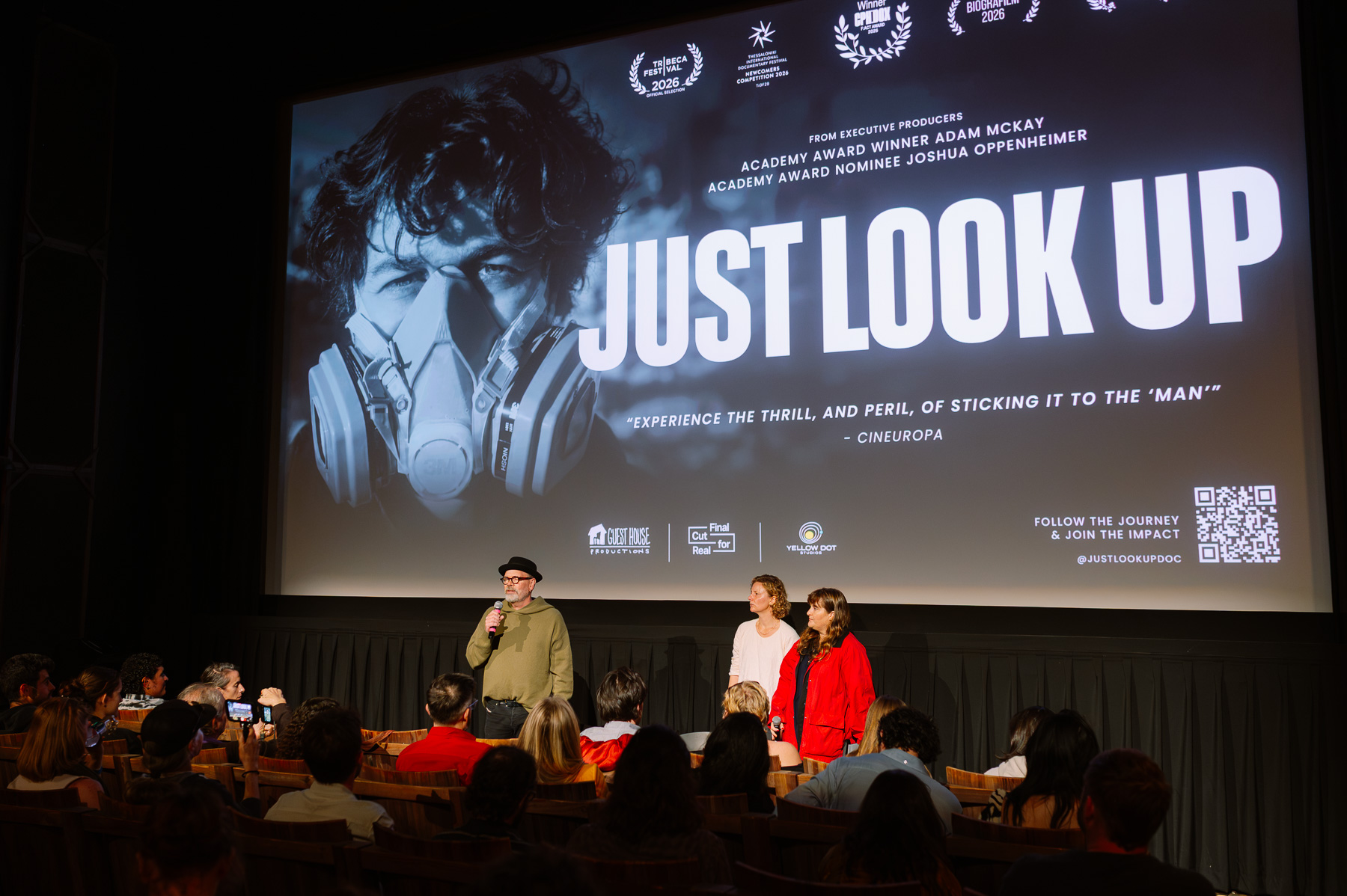 Speakers on stage in front of the Just Look Up title screen