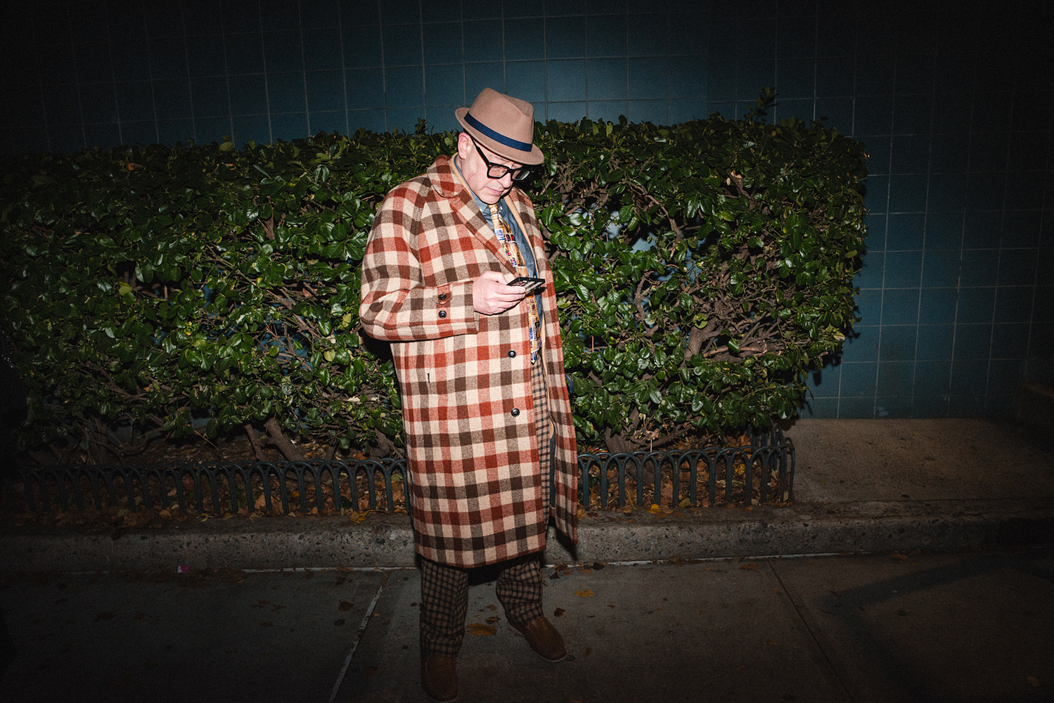Guest checking his phone on the sidewalk at night