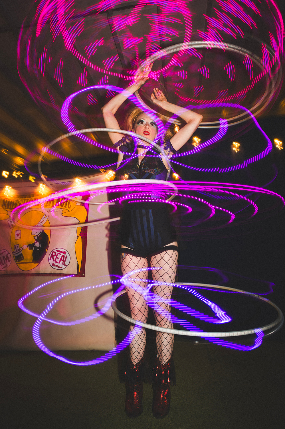 Long-exposure hula hoop performer with glowing light trails
