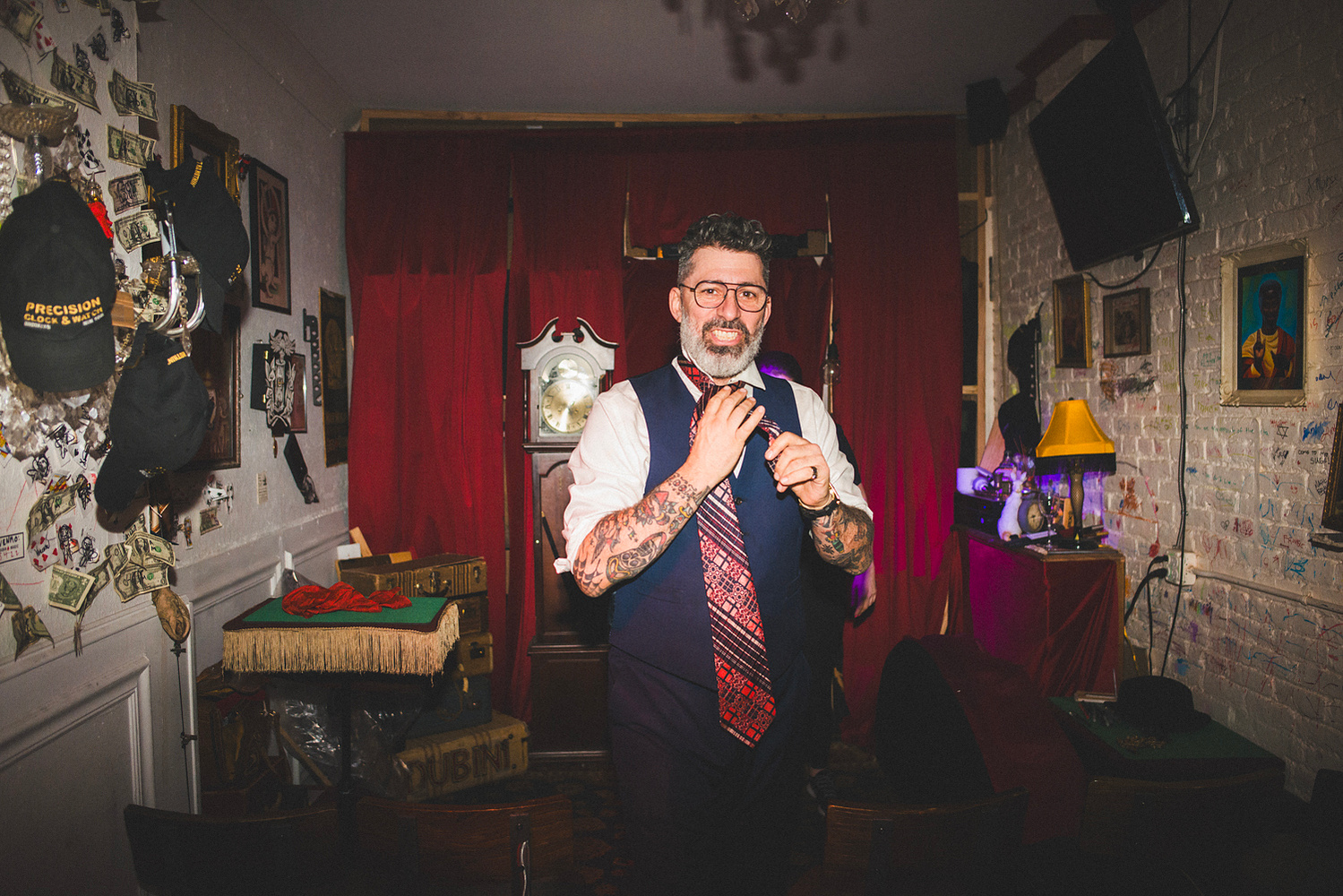 The magician adjusting his tie in front of the red curtain