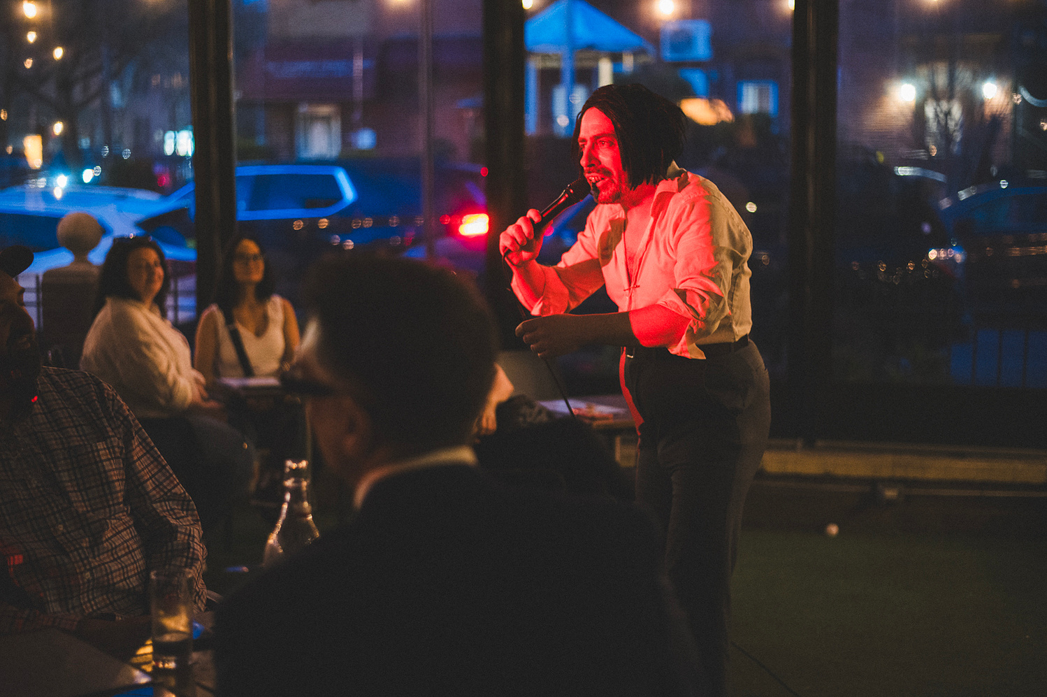 Performer speaking into a microphone under red light