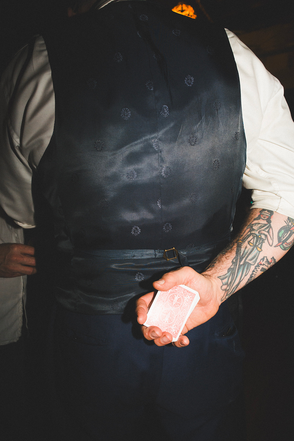 Hand holding a deck of playing cards behind a satin vest