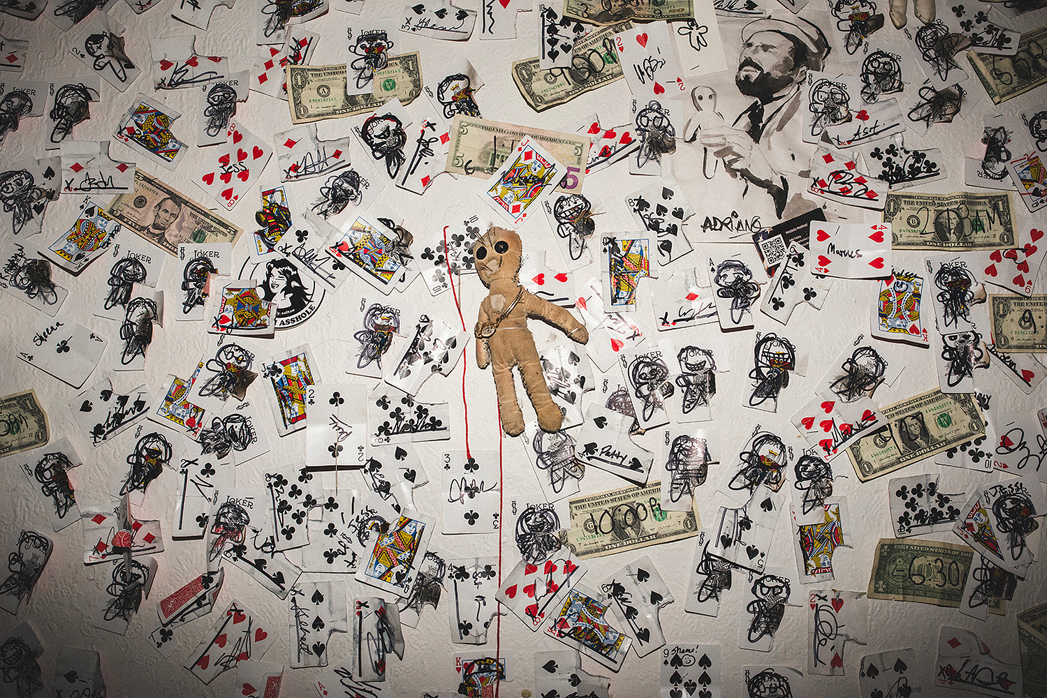 Wall detail covered in playing cards, cash and signatures