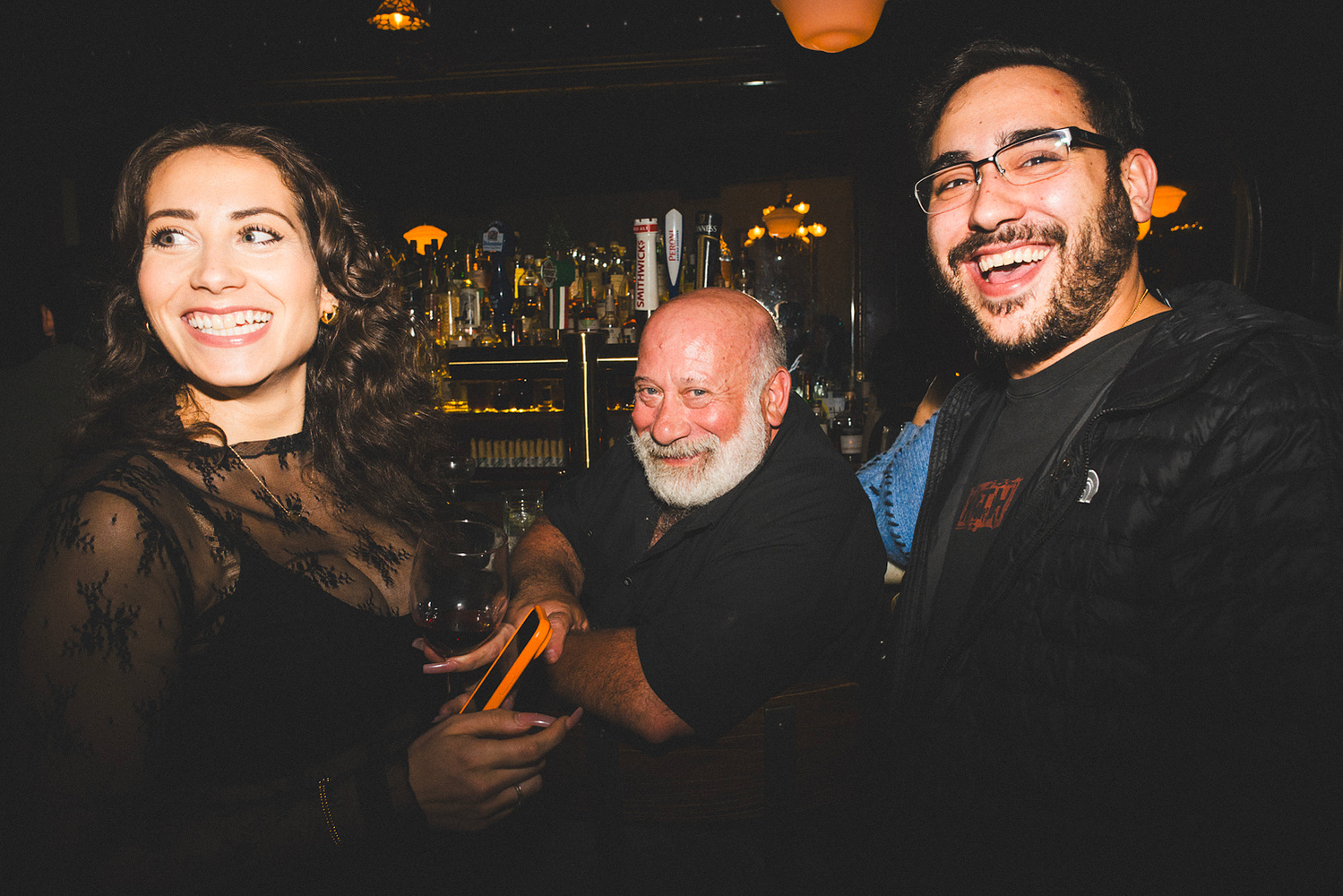 Three guests posing together at the bar