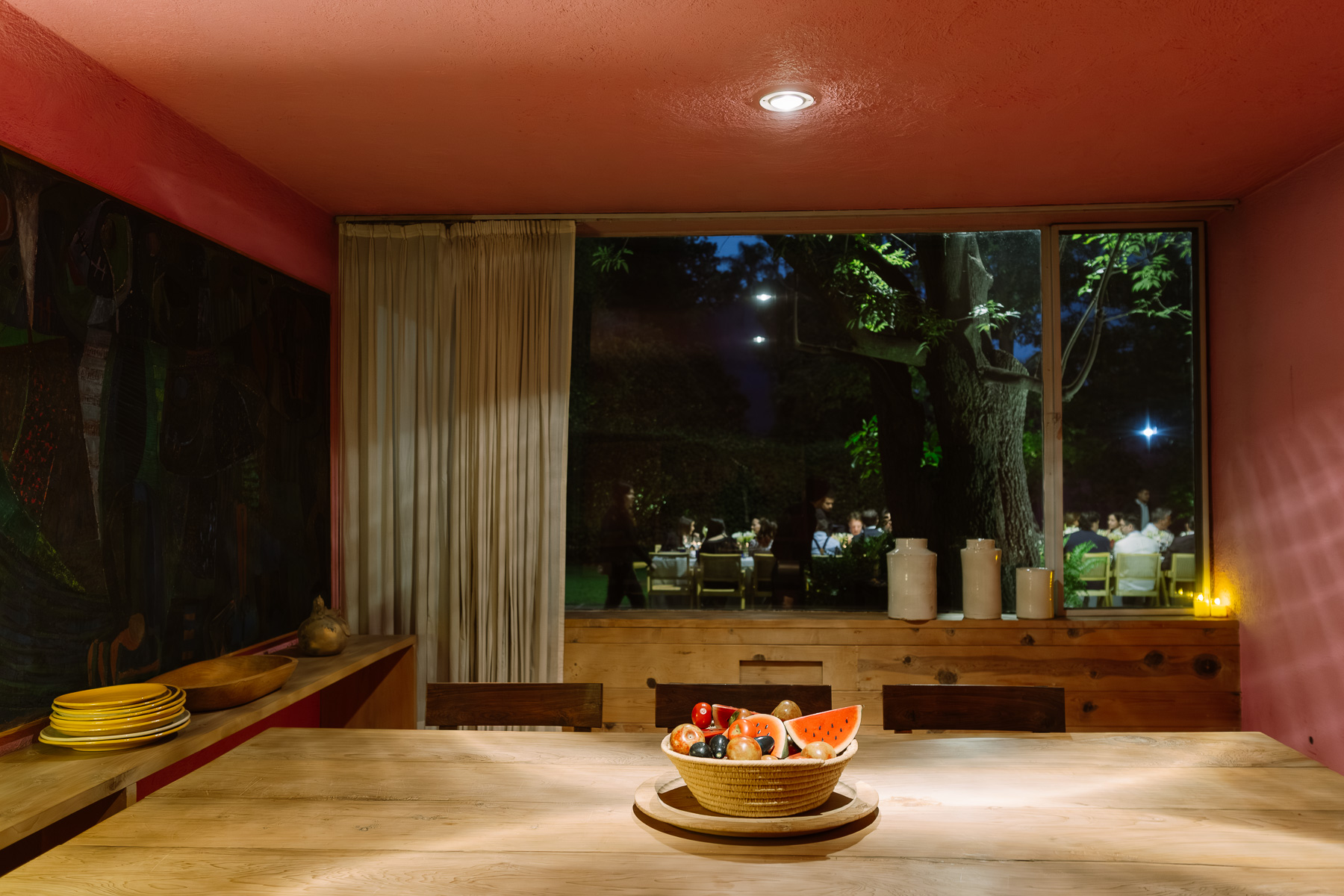Dining room at night with a fruit bowl and garden view