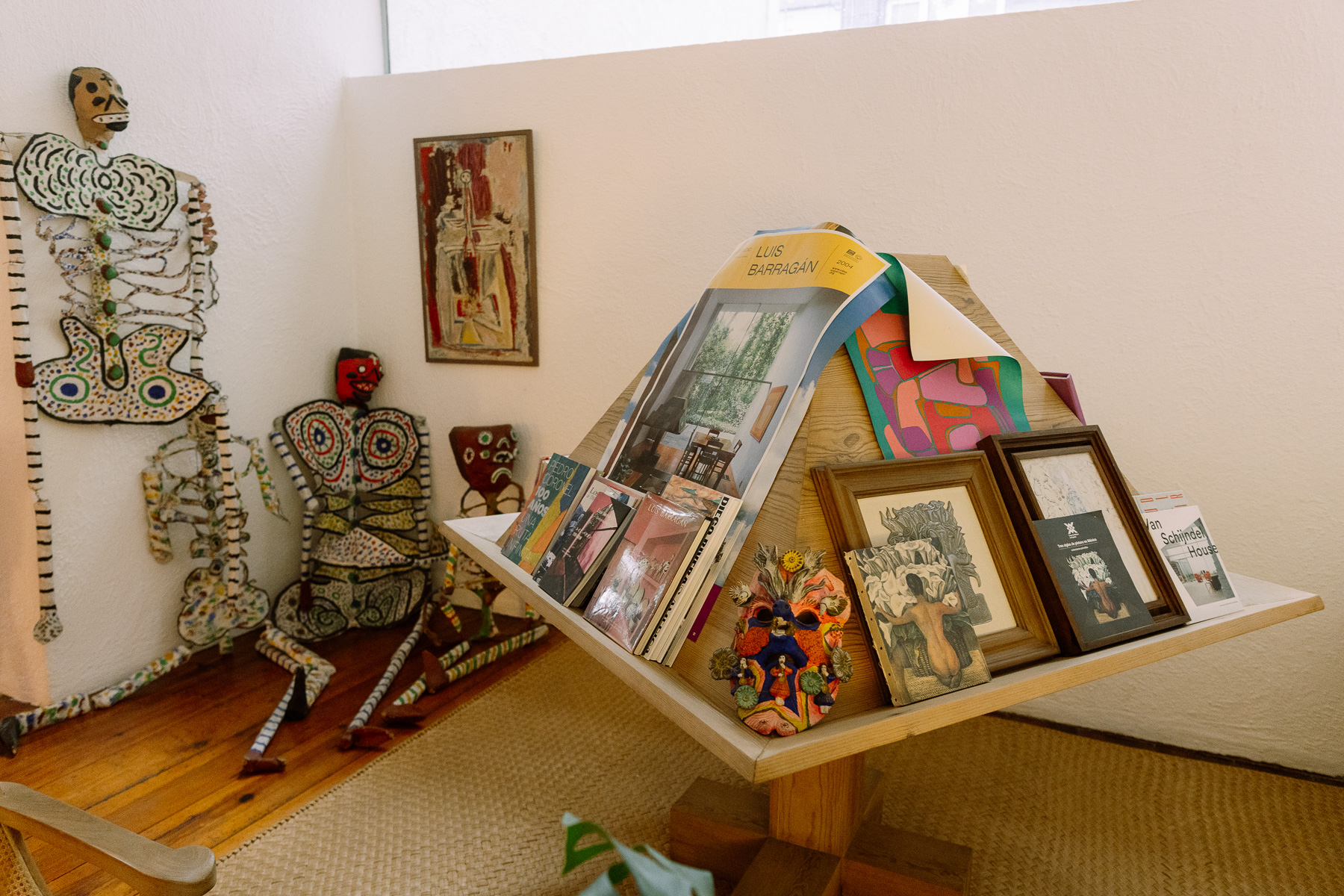 Folk art skeletons and Barragán books on a wooden stand