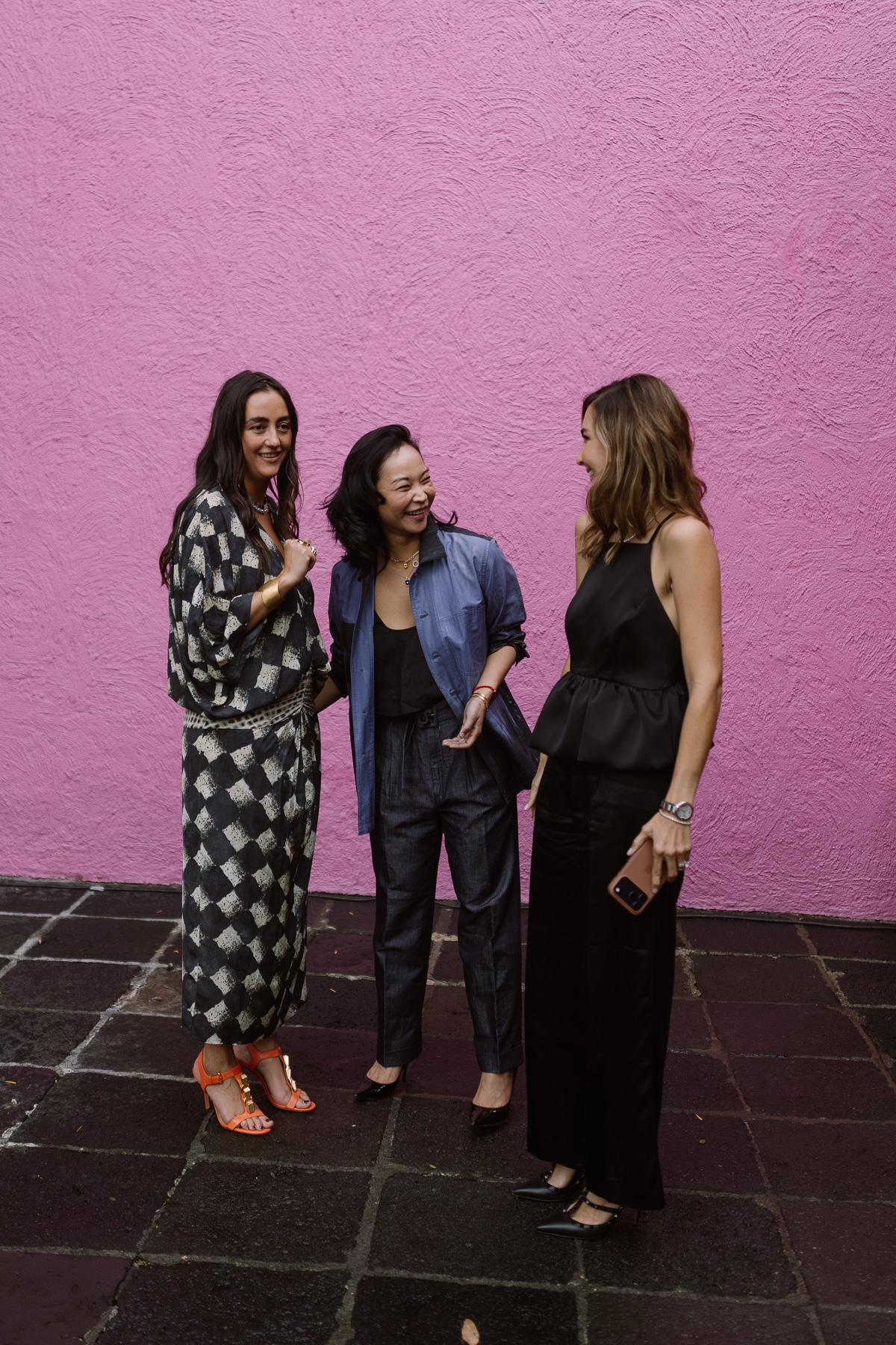 Three guests talking on the slate patio against the pink wall