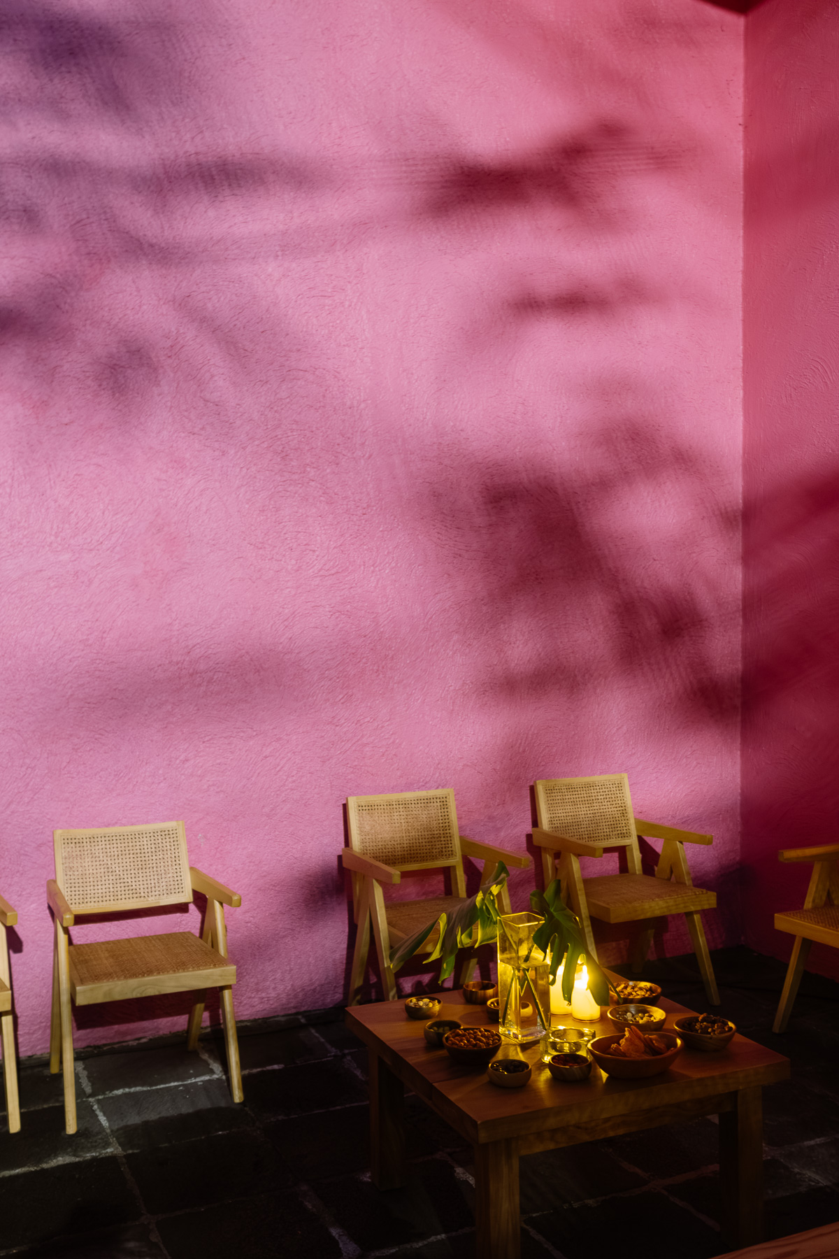 Lounge seating by candlelight against the pink wall